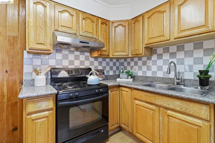 Kitchen featuring black range with gas stovetop, backsplash, and light countertops