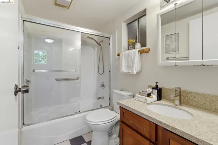 Full bath featuring vanity, enclosed tub / shower combo, and tile patterned floors