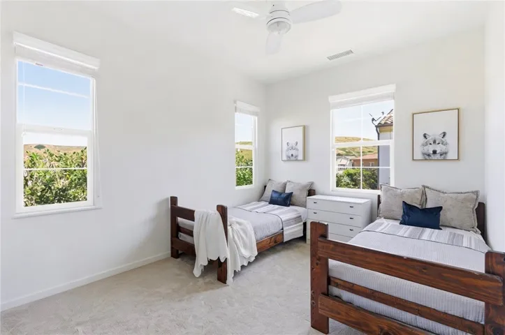 Light-filled secondary bedroom featuring multiple windows, soft natural light, and a flexible layout perfect for guests, kids, or a home office setup.