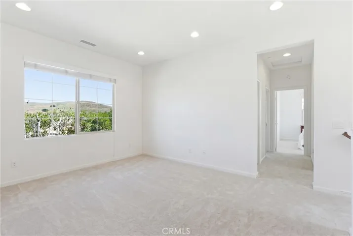 BEFORE: Spacious primary bedroom offering a clean, open layout with abundant natural light and peaceful hillside views. VIRTUALLY EDITED