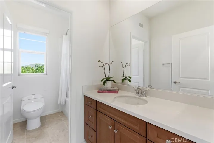 Light and bright secondary bathroom featuring a clean vanity, shower/tub combination, and natural light from a nearby window.