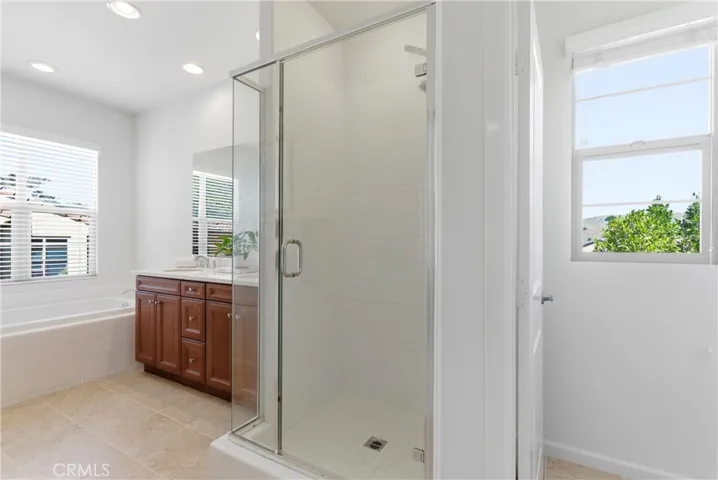 Primary bathroom complete with a separate glass-enclosed shower, dual sinks, and a functional layout designed for everyday comfort.