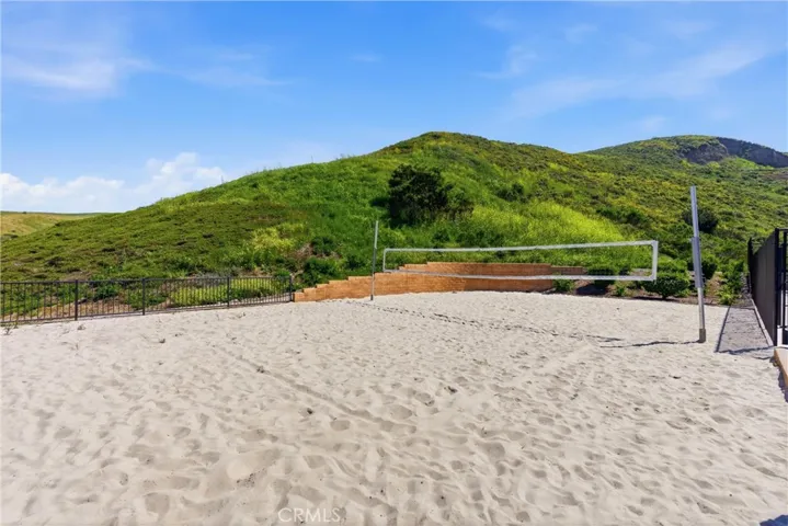 Private community sand volleyball court set against rolling hills, offering a unique recreational space for residents and guests.
