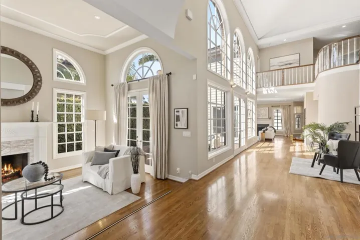 Expansive and light-filled, this grand living space blends soaring ceilings, arched windows, and warm hardwood floors, creating an elegant flow between intimate comfort and open, airy sophistication.