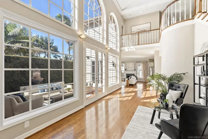 Walls of glass and soaring arches invite sunlight to pour across warm hardwood floors, creating a seamless connection to the outdoor terrace and a sense of openness that defines refined California living.