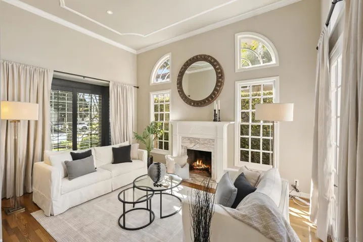 A refined gathering space bathed in natural light, where arched windows, soft neutral tones, and a glowing fireplace create an atmosphere of effortless comfort and elevated everyday living.