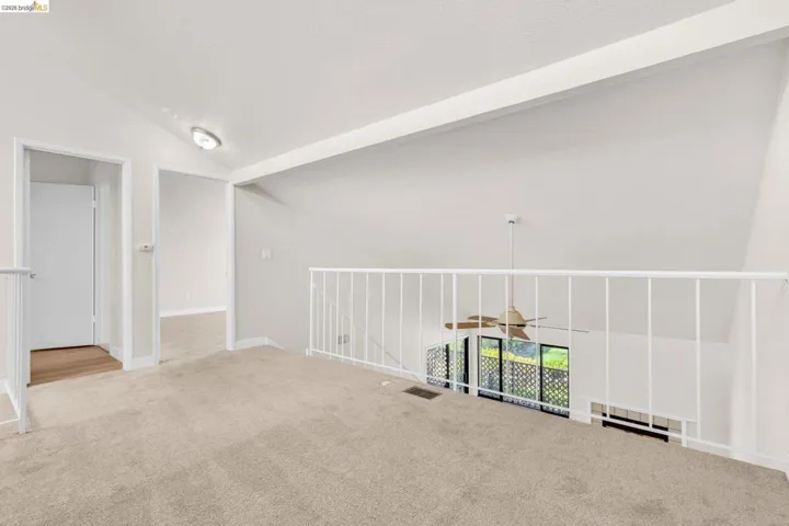 Carpeted spare room with vaulted ceiling and ceiling fan