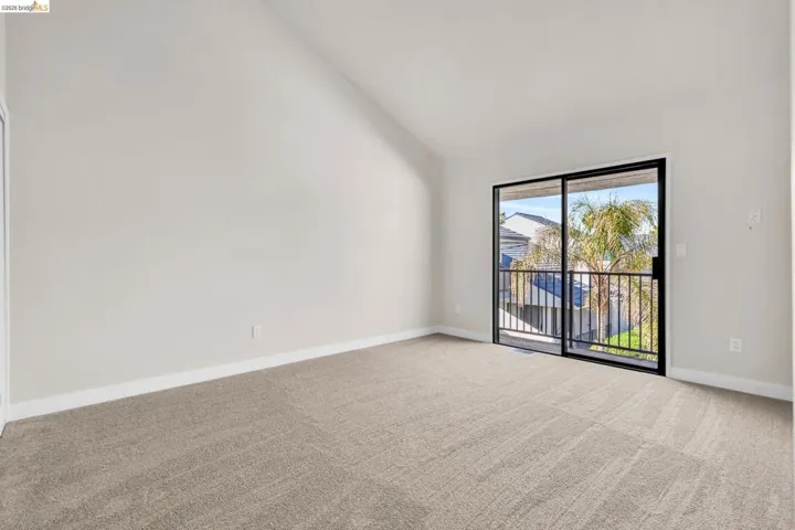 Carpeted spare room with vaulted ceiling and baseboards