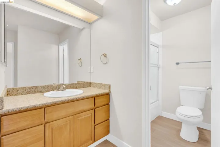 Full bath featuring vanity, light wood-style floors, and bath / shower combo with glass door