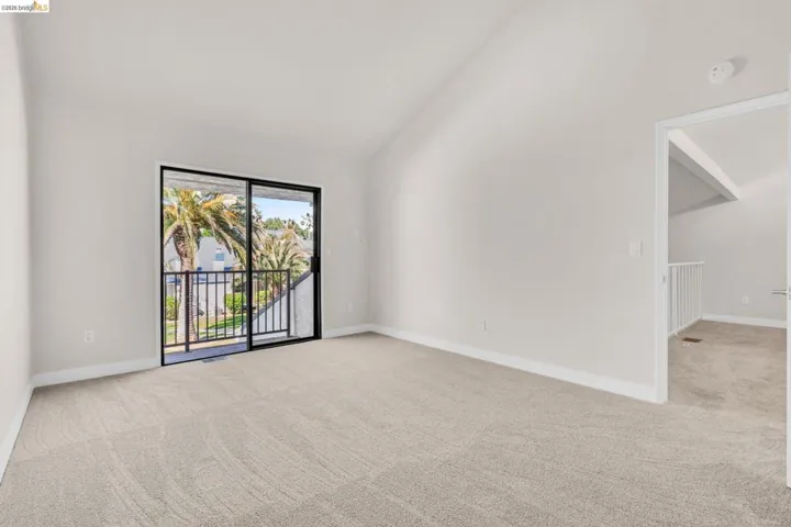 Unfurnished room featuring light carpet and lofted ceiling