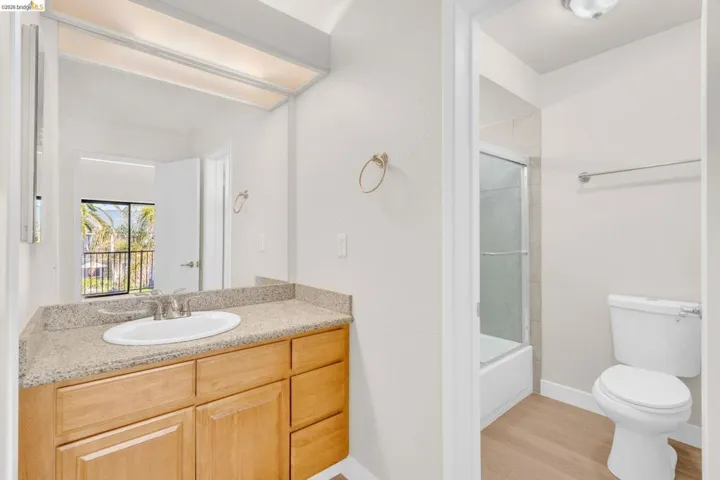 Full bathroom featuring vanity, light wood-style floors, and bath / shower combo with glass door