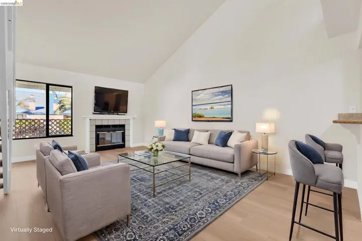 Living area featuring a fireplace, light wood-style floors, and vaulted ceiling