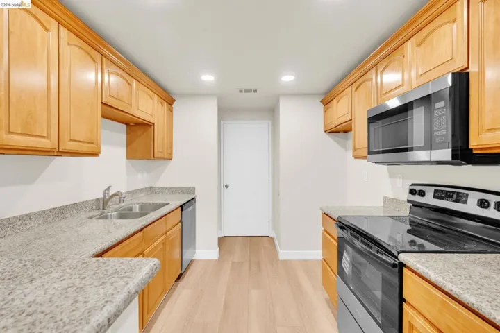 Kitchen featuring stainless steel appliances, light stone countertops, light wood finished floors, recessed lighting, and light wood finish cabinetry