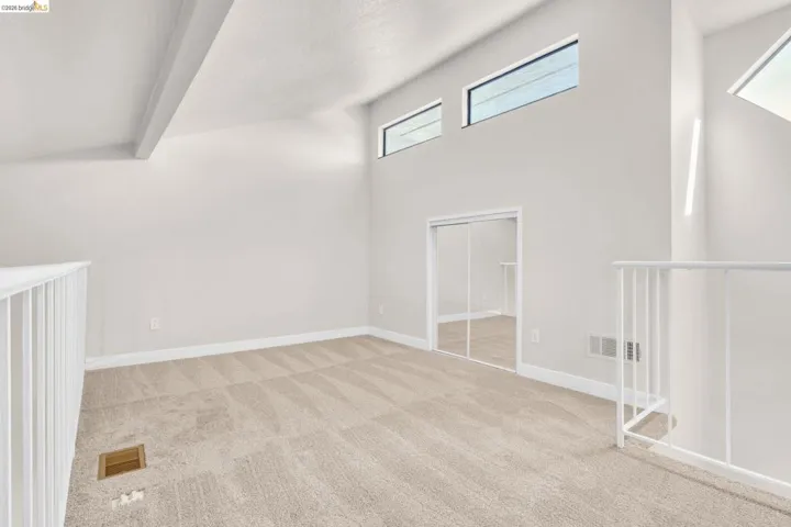 Additional living space with light carpet and a high ceiling