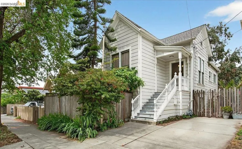 View of front of home featuring stairs and a shingled roof
