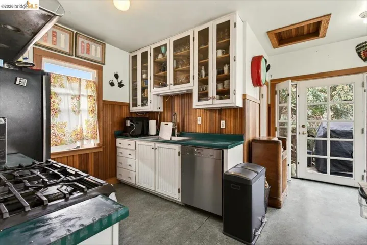 Kitchen with white cabinetry, plenty of natural light, extractor fan, stainless steel appliances, and wainscoting