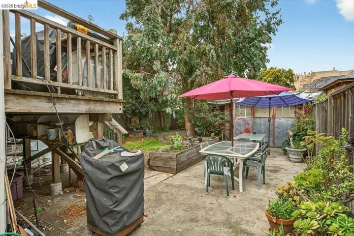 Fenced backyard with outdoor dining area, a vegetable garden, a patio area, and a grill