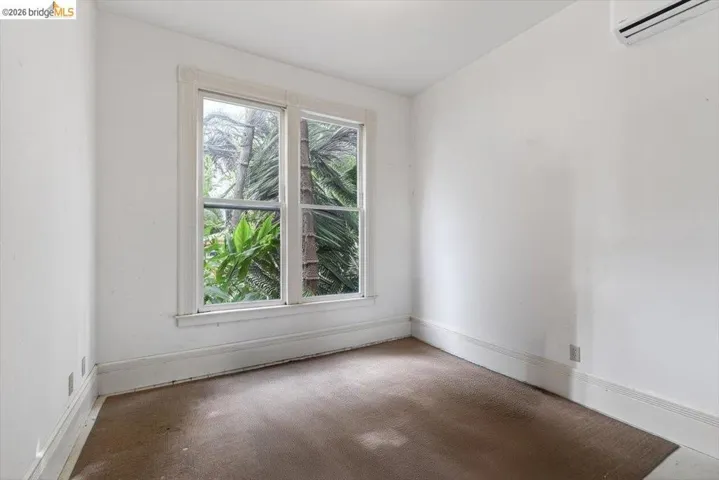 Carpeted spare room featuring a wall mounted mini split and baseboards