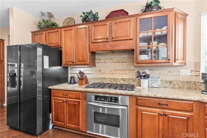 Elegant mullion glass-front cabinetry and professional grade gas range with custom tile backsplash.