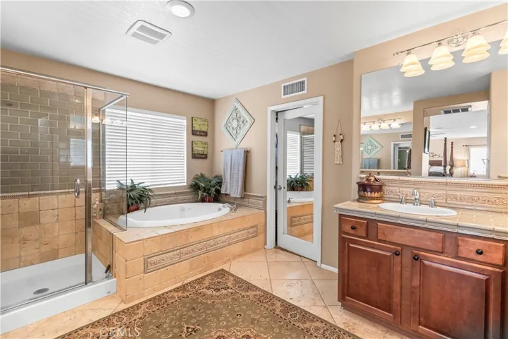 Second sink area in the primary ensuite plus a soaking tub and shower with custom stonework.
