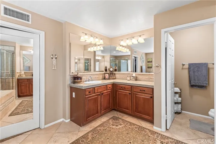 Primary ensuite bathroom with two separate sink areas and mirrored closet door.
