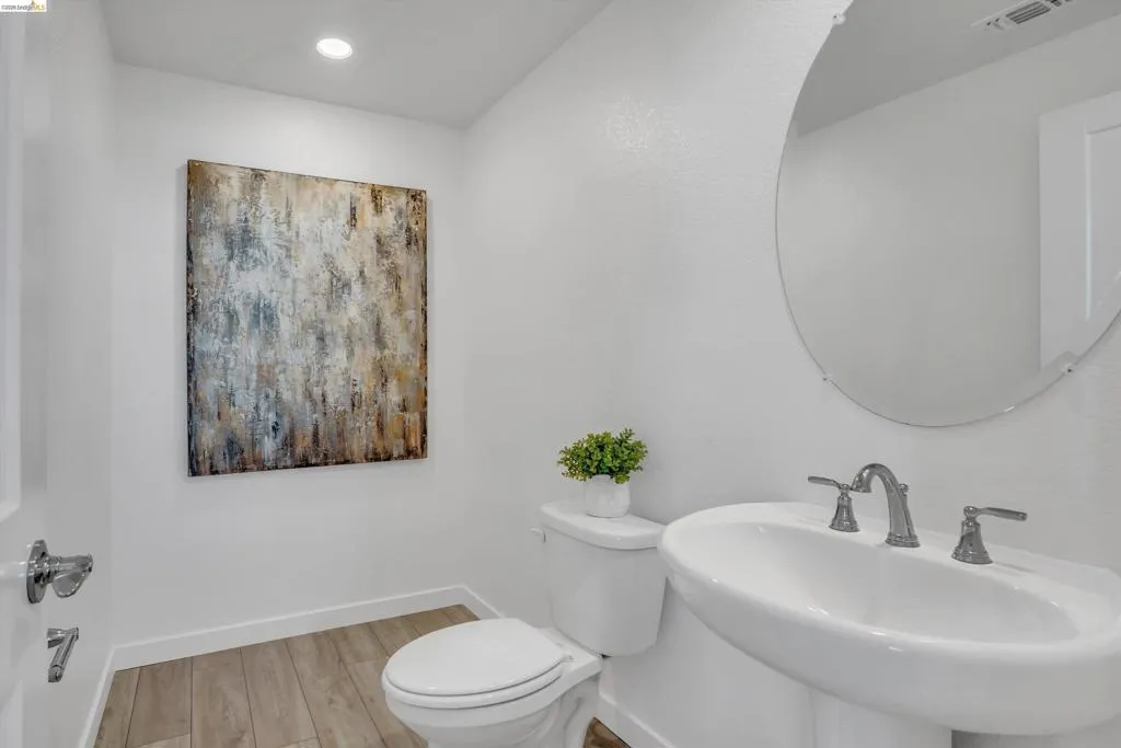 Half bath with light wood finished floors and recessed lighting