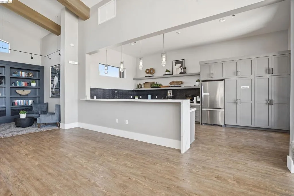 Kitchen with freestanding refrigerator, a peninsula, light countertops, gray cabinets, and decorative backsplash