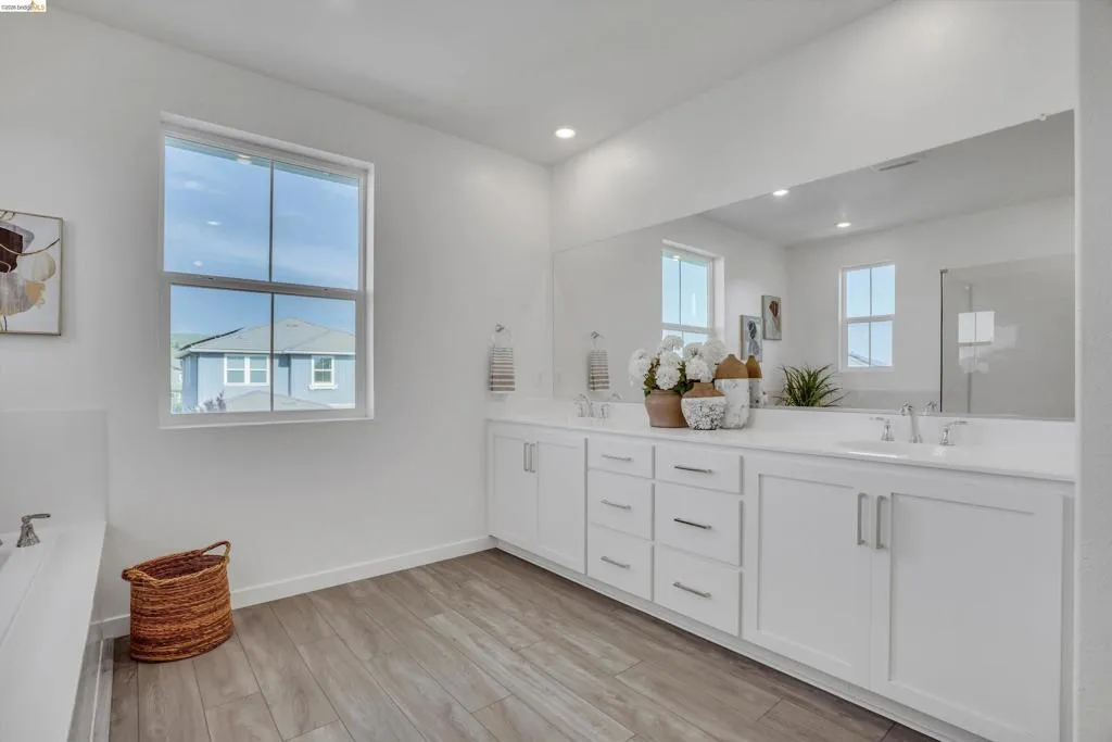 Full bathroom with double vanity, light wood-style floors, and recessed lighting