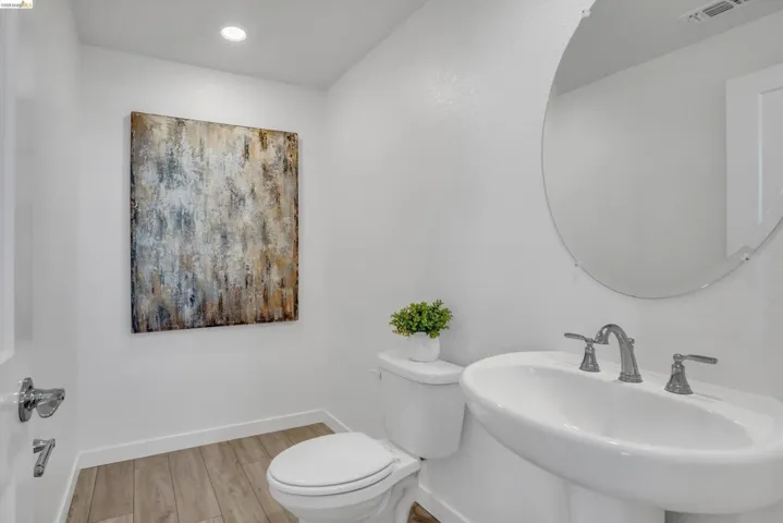 Half bath with light wood finished floors and recessed lighting
