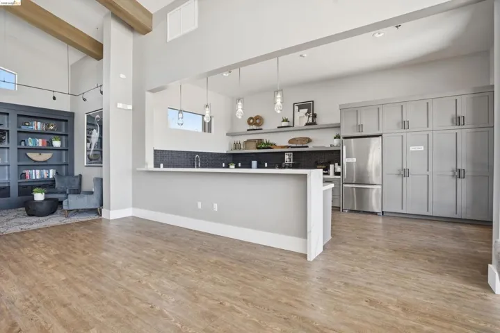 Kitchen with freestanding refrigerator, a peninsula, light countertops, gray cabinets, and decorative backsplash