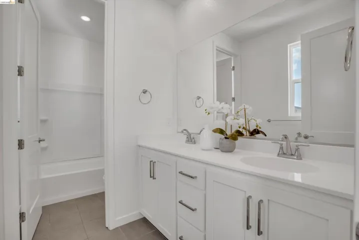 Full bathroom with double vanity, light tile patterned flooring, shower / washtub combination, and recessed lighting
