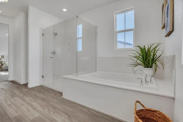 Full bathroom featuring a bath, a stall shower, light wood-style floors, and recessed lighting