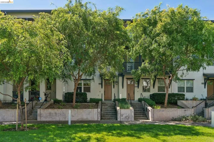 View of property hidden behind natural elements with stucco siding and a balcony