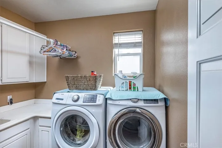 Large indoor laundry room with multiple cabinets and built-in sink.