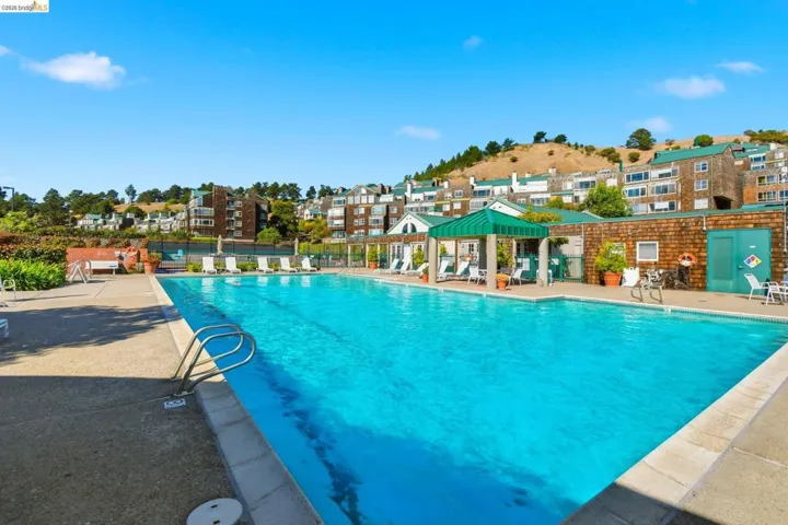 Community pool with a patio area and a residential view