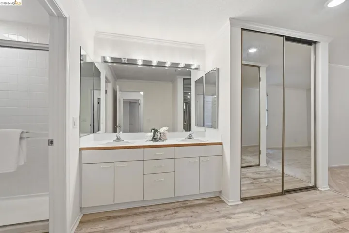Full bathroom featuring double vanity, light wood-style floors, and crown molding