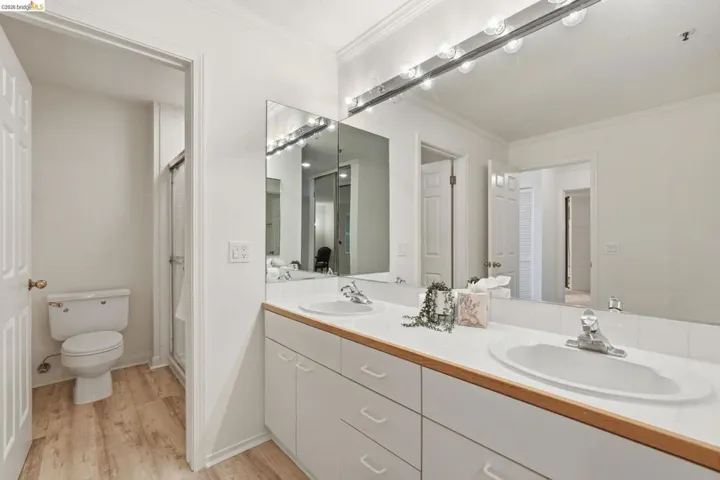 Bathroom featuring crown molding, a stall shower, double vanity, and light wood finished floors