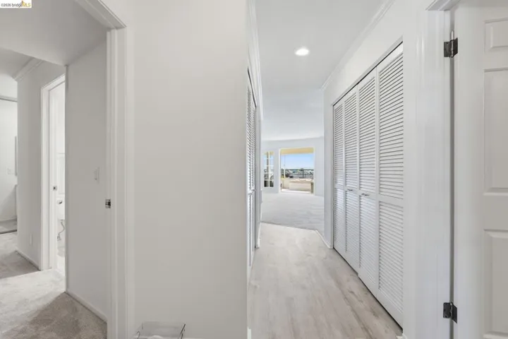 Corridor featuring ornamental molding, light carpet, light wood-type flooring, and recessed lighting