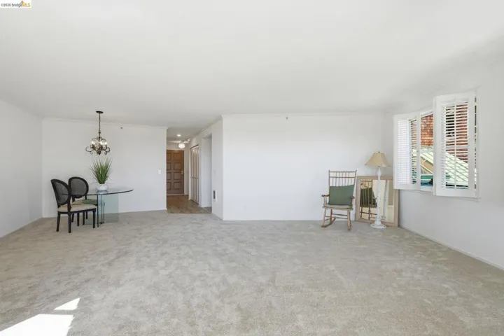 Spare room with light carpet, crown molding, and a chandelier