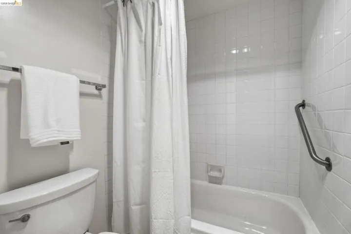 Bathroom featuring toilet and shower / tub combo with curtain