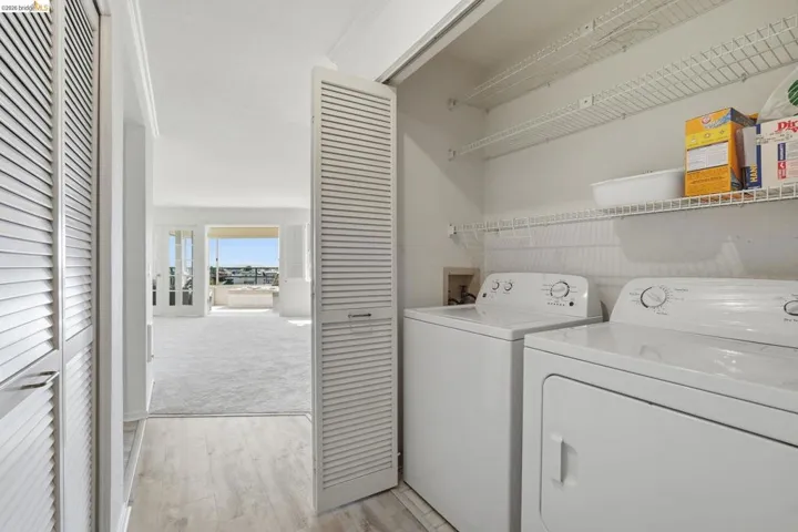 Laundry area featuring light wood-style floors, washer and dryer, and light carpet