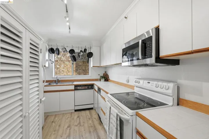 Dual tone kitchen featuring white appliances, light wood-style floors, dual tone cabinets, and tile counters