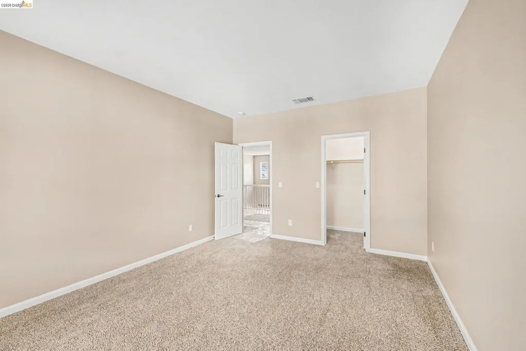 Unfurnished bedroom with a walk in closet and light colored carpet