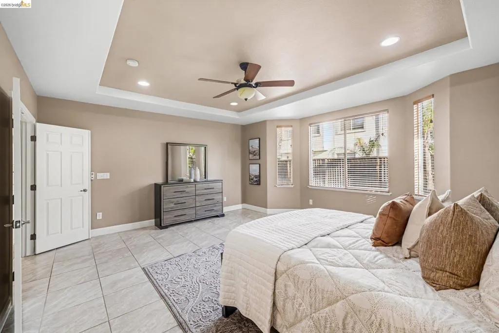 Bedroom featuring a raised ceiling, recessed lighting, ceiling fan, and light tile patterned floors