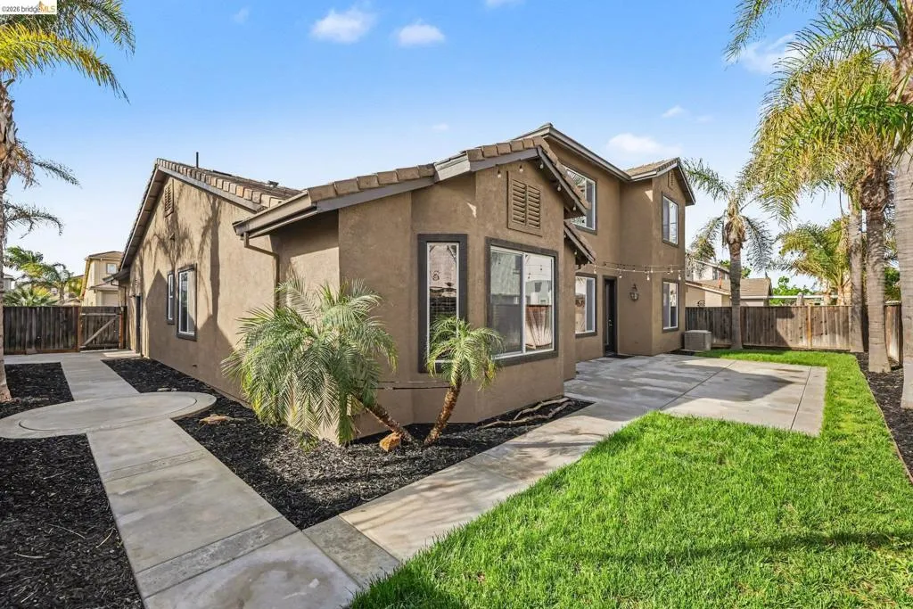 View of side of property featuring a fenced backyard, stucco siding, a patio area, and a gate