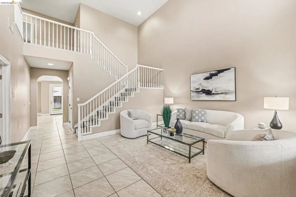 Living area with arched walkways, recessed lighting, light tile patterned flooring, and a high ceiling