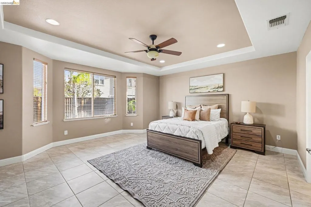 Bedroom featuring a tray ceiling, ceiling fan, light tile patterned floors, and recessed lighting