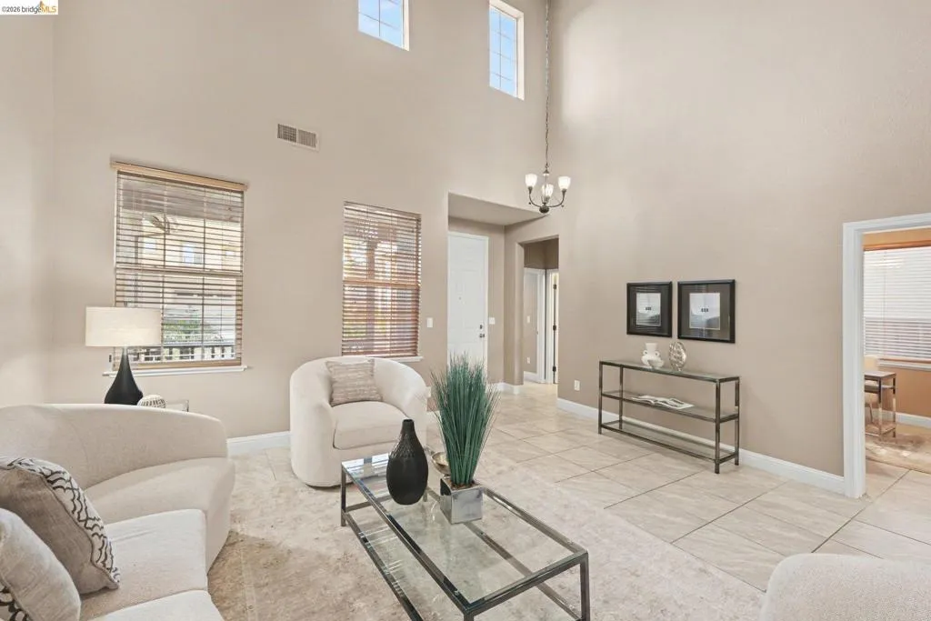 Living area with suspended lighting, light tile patterned flooring, and a high ceiling