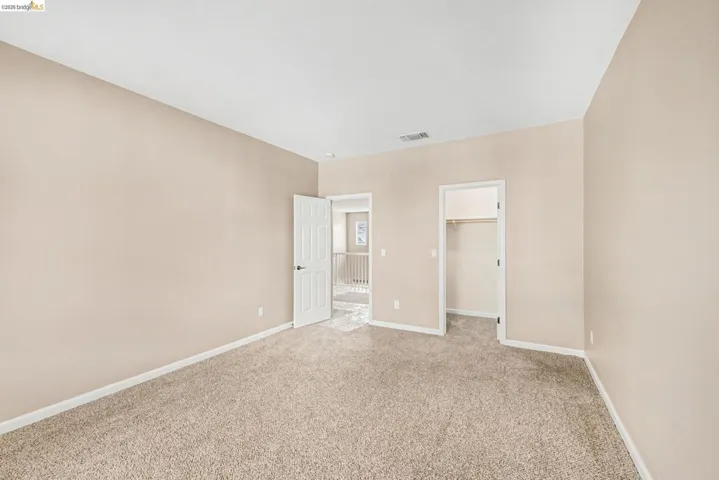 Unfurnished bedroom with a walk in closet and light colored carpet