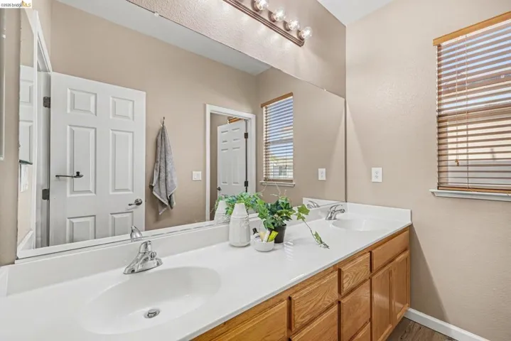 Full bathroom with double vanity and a textured wall